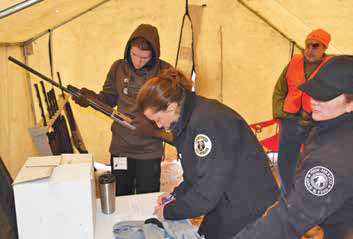 Jennifer Morgan, the NMDGF Hunter Education Program coordinator (center) and Jessica Fisher, the Shooting Program coordinator (right) check out shotguns to youth hunters. New Mexico Wildlife magazine, NMDGF