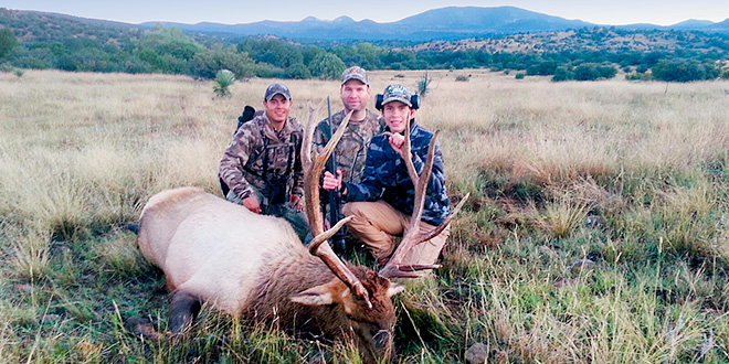 Nathan Kempton (right), the son of Game and Fish Conservation Officer Brandon Kempton (center) poses with the 7x7 elk he harvested in 2015. Brandon and fellow Conservation Officer Adan Jacquez noticed an ear tag on the elk and it turned out to be the same animal that had been freed from beneath a cattle guard three years earlier.
