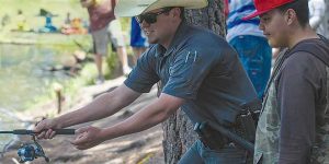 Trevor Nygren helps a young angler learn casting skills. Department photo by Tristanna Bickford. New Mexico Wildlife magazine Winter 2018 Vol61, Num1, New Mexico Department of Game and Fish.