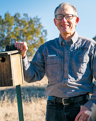 Kevin Holladay, former conservation education program manager, checks a bluebird nesting box. Department photo by Martin Perea. 