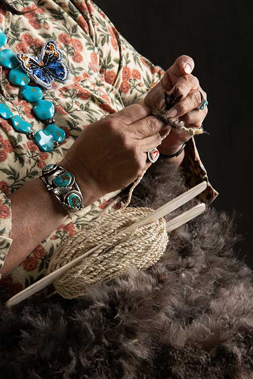 Mary Weahkee, an archeologist and anthropologist with the Department of Cultural Affairs in Santa Fe, weaved a blanket with thousands of feathers from turkey hunters. Department photo by Martin Perea. 